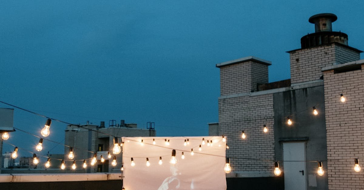 A group of friends enjoys a rooftop movie night under string lights with a projector and cozy blankets.