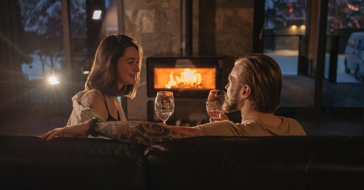 A couple enjoying a cozy, romantic evening indoors by the fireplace with wine glasses.